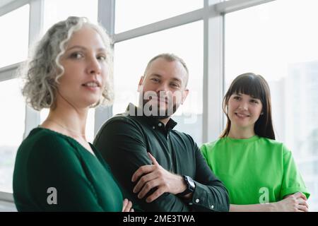 Portrait of three confident business people in green clothing on office floor Stock Photo