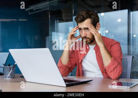 Frustrated businessman depressed at workplace working on laptop, man in shirt upset and sad displeased with bad work results and achievement inside office. Stock Photo