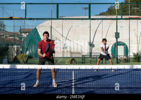 Man with friend playing paddle tennis at sports court Stock Photo