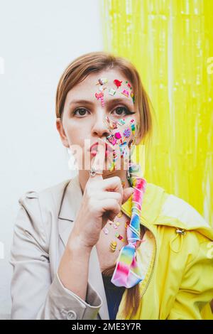 Woman with finger on lips in front of two tone wall Stock Photo