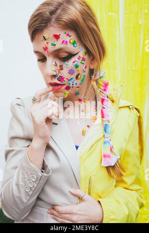 Thoughtful woman with stickers on face in front of wall Stock Photo