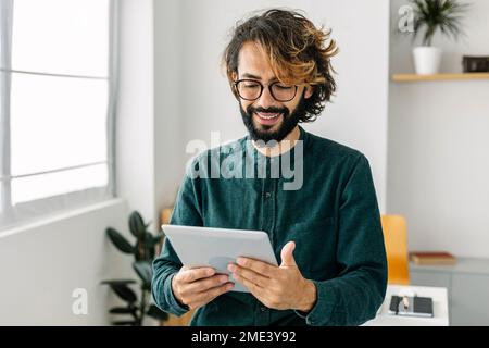 Happy freelancer using tablet PC in office Stock Photo