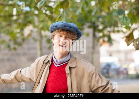 Happy young man wearing flat cap and jacket Stock Photo