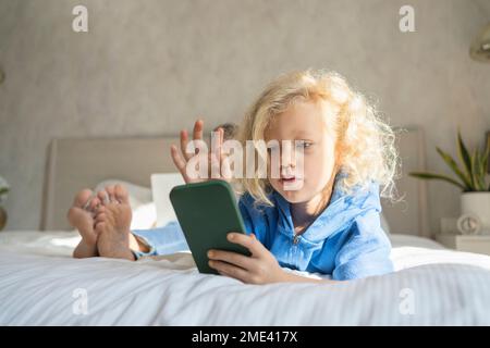 Girl using smart phone lying on bed at home Stock Photo