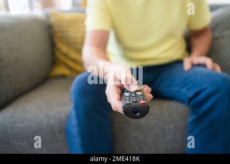 Hand of man holding remote control on sofa Stock Photo