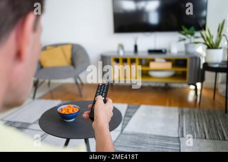 Man using TV remote control in living room at home Stock Photo