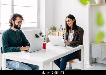 Happy business colleagues using laptop at desk in office Stock Photo