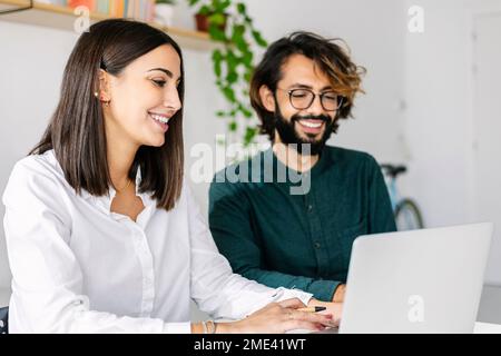 Happy business colleagues working on laptop at office Stock Photo