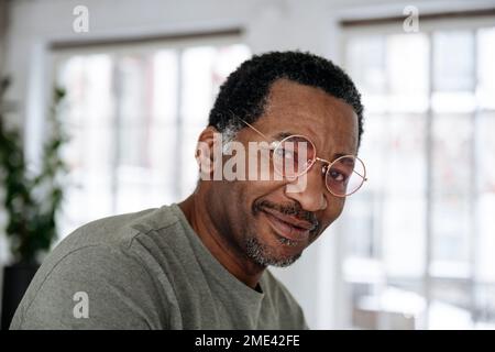Smiling mature man wearing pink glasses at home Stock Photo