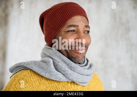 Smiling man wearing scarf and knit hat Stock Photo