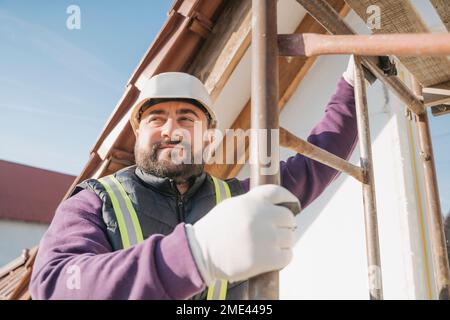 Smiling construction worker holding ladder Stock Photo