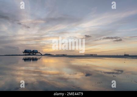 Germany, Schleswig-Holstein, St. Peter-Ording, Clouds over coastal stilt houses at dusk Stock Photo