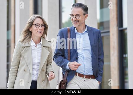 Happy mature business people walking together outside building Stock Photo