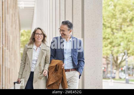 Happy business people walking together on footpath Stock Photo