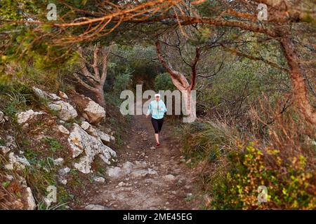 Sporty woman running in forest in morning Stock Photo