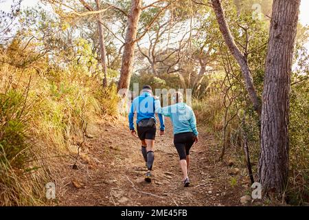 Couple walking together on dirt road in forest Stock Photo