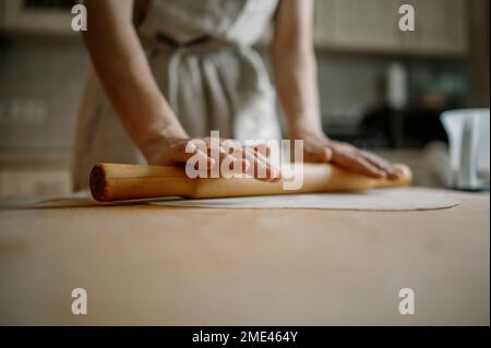Woman rolling dough for dumplings in kitchen at home Stock Photo