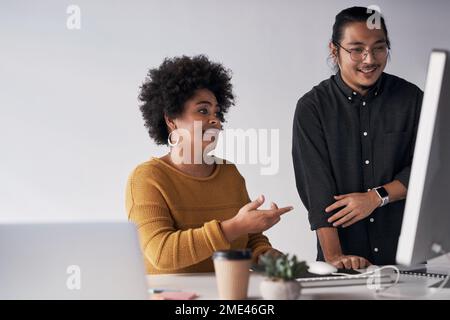 Doesnt this look good. a two young coworkers working on a computer together in the office. Stock Photo