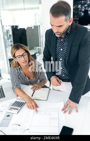 Architects discussing over blueprints in office Stock Photo