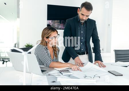 Architect explaining coworker over blueprint in office Stock Photo