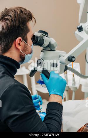 Dentist examining patient's teeth with microscope in clinic Stock Photo