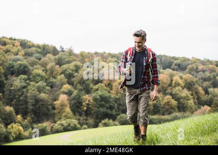 Mature man using smart phone walking on grass Stock Photo