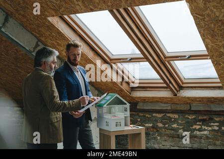 Architect pointing over blueprint and explaining colleague at construction site Stock Photo