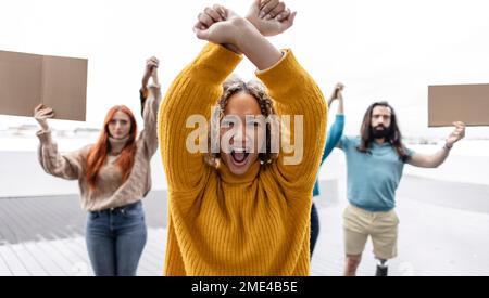 Young woman protesting with arms raised Stock Photo