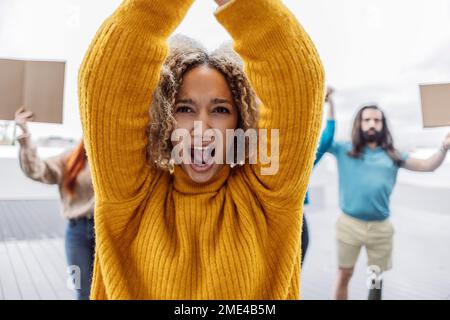 Young woman with arms raised protesting by activists Stock Photo
