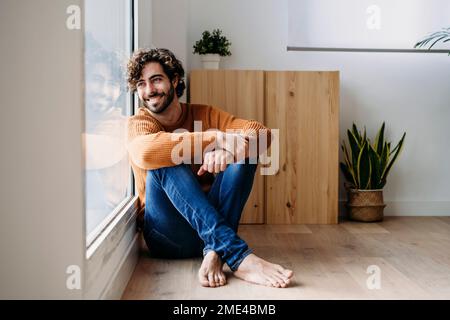 Happy young man looking through glass window Stock Photo