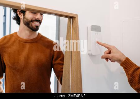 Happy young man setting alarm system at home Stock Photo