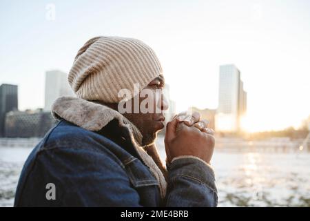 Man wearing knit hat warming hands in winter Stock Photo