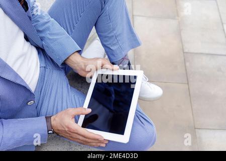 Hands of businessman holding tablet PC sitting on bench Stock Photo
