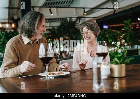 Senior man and woman sitting at table with wineglass in cafe Stock Photo