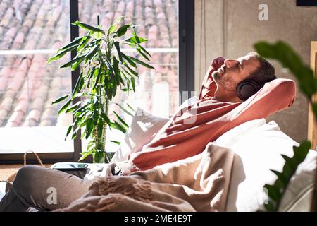 Man wearing headphones relaxing on sofa at home Stock Photo