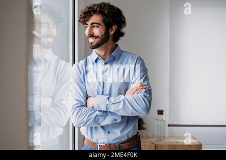 Thoughtful young businessman looking through window in office Stock Photo