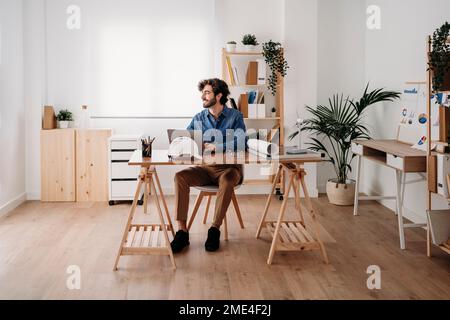 Smiling engineer working on desk with laptop in office Stock Photo