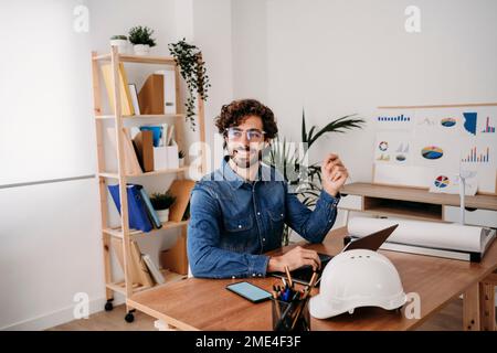 Thoughtful young engineer with laptop on desk in office Stock Photo