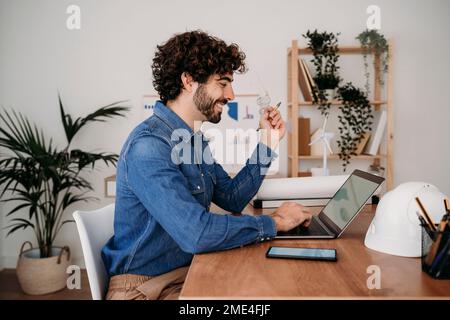 Smiling young engineer working on laptop in office Stock Photo
