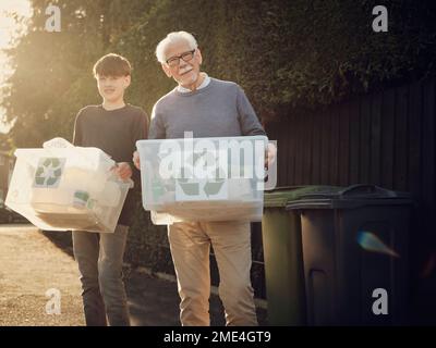 Grandfather and son standing outdoors carrying recycling boxes with separated waste Stock Photo