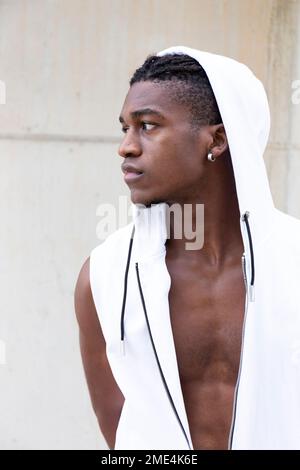 Man wearing white hooded shirt in front of wall Stock Photo