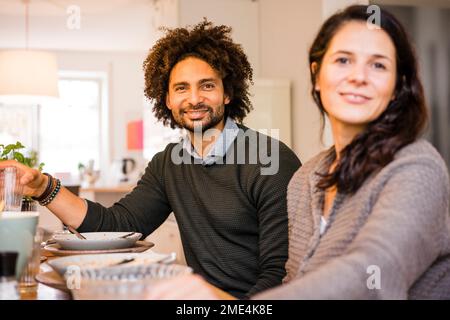 Happy man and woman sitting at dining table Stock Photo