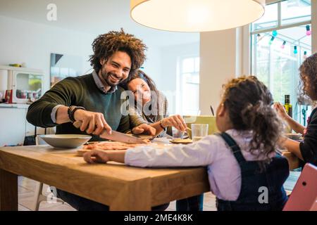 Happy family having lunch together on dining table at home Stock Photo