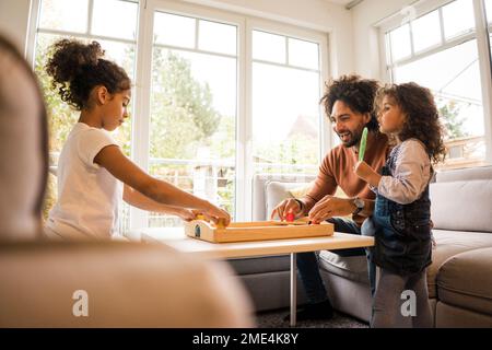 Happy father playing board games with daughters at home Stock Photo