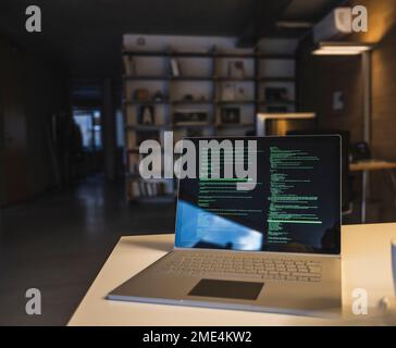 Laptop with data on screen kept at desk in office Stock Photo