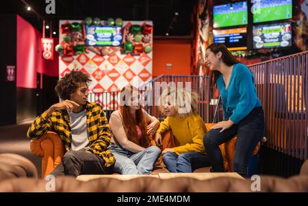 Multiracial friends having fun sitting on sofa at bowling alley Stock Photo