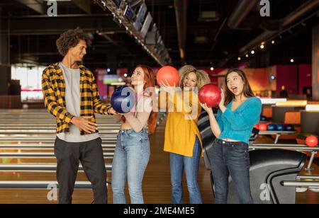 Happy man with women with balls enjoying at bowling alley Stock Photo