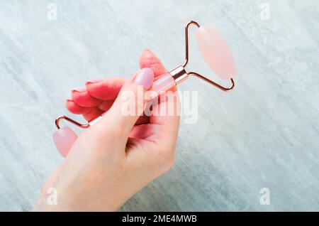 Rose Quartz Face Roller in Woman Hands, Facial Lifting Scraping Massage Treatment Stock Photo