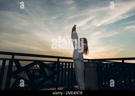 Woman holding LED bulb standing under sky Stock Photo