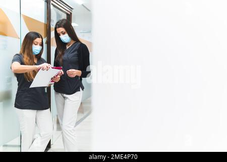 Young dental assistants discussing over documents standing at clinic Stock Photo